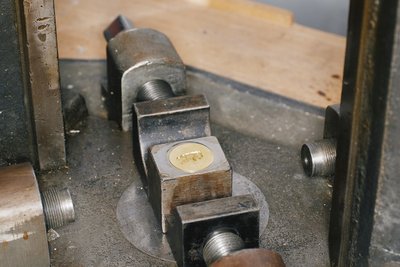 Eine Metallmütze nach der Prägung, sie liegt noch in der Prägemaschine.
