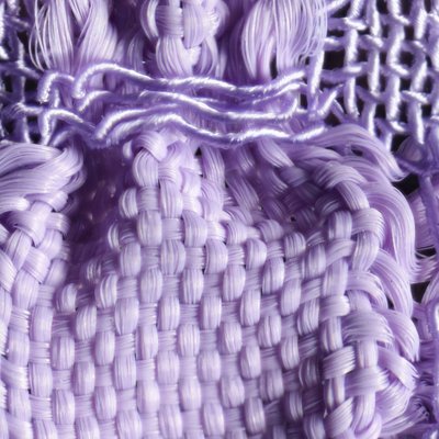 Detailaufnahme eines lilafarbenen Gewebes. Durch zwei unterschiedlich elastische Garne, Gummilitze und Seide, tritt das Blasenmuster des Stoffes besonders hervor. 