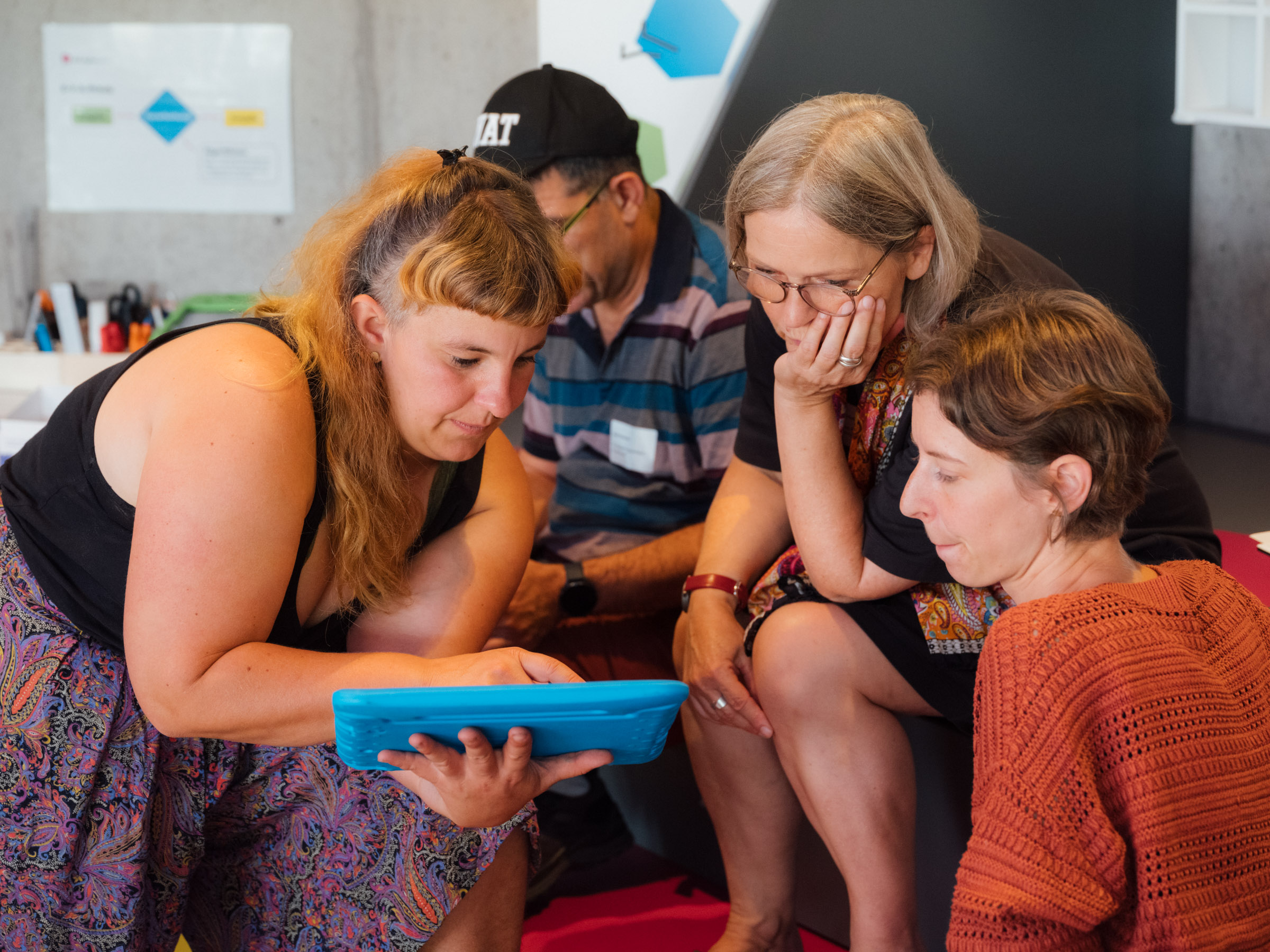 Drei Frauen beugen sich über ein tablet.