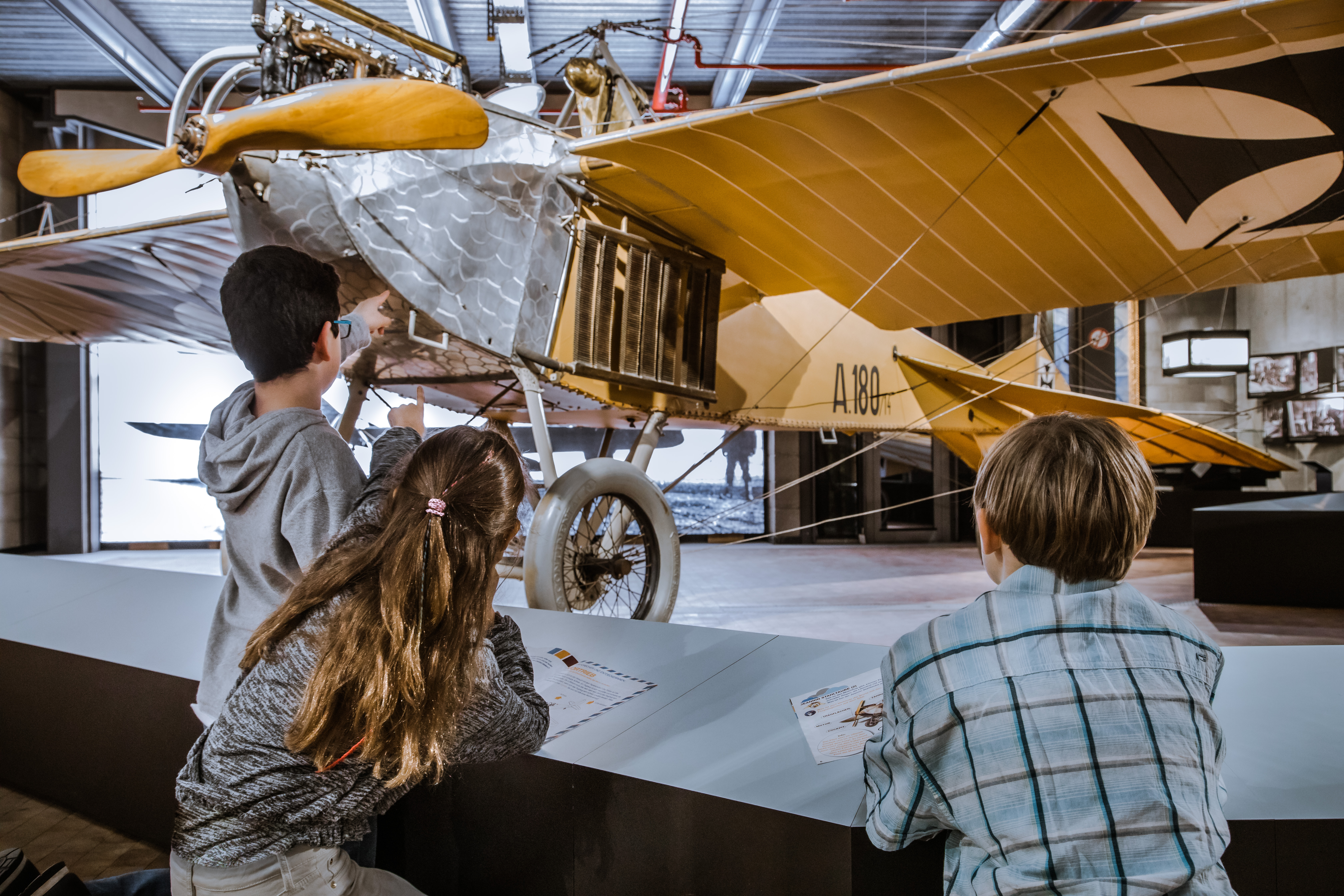 Drei Kinder betrachten ein elegantes Flugzeug  aus Metall.