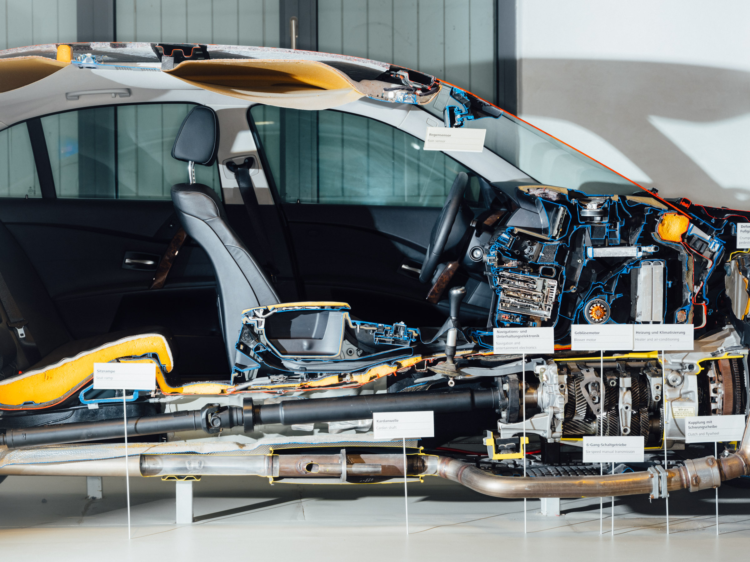 Die Hälfte eines quer durchgeschnittenen Autos zeigt Polstermaterial, Verkabelungen und Motor. 