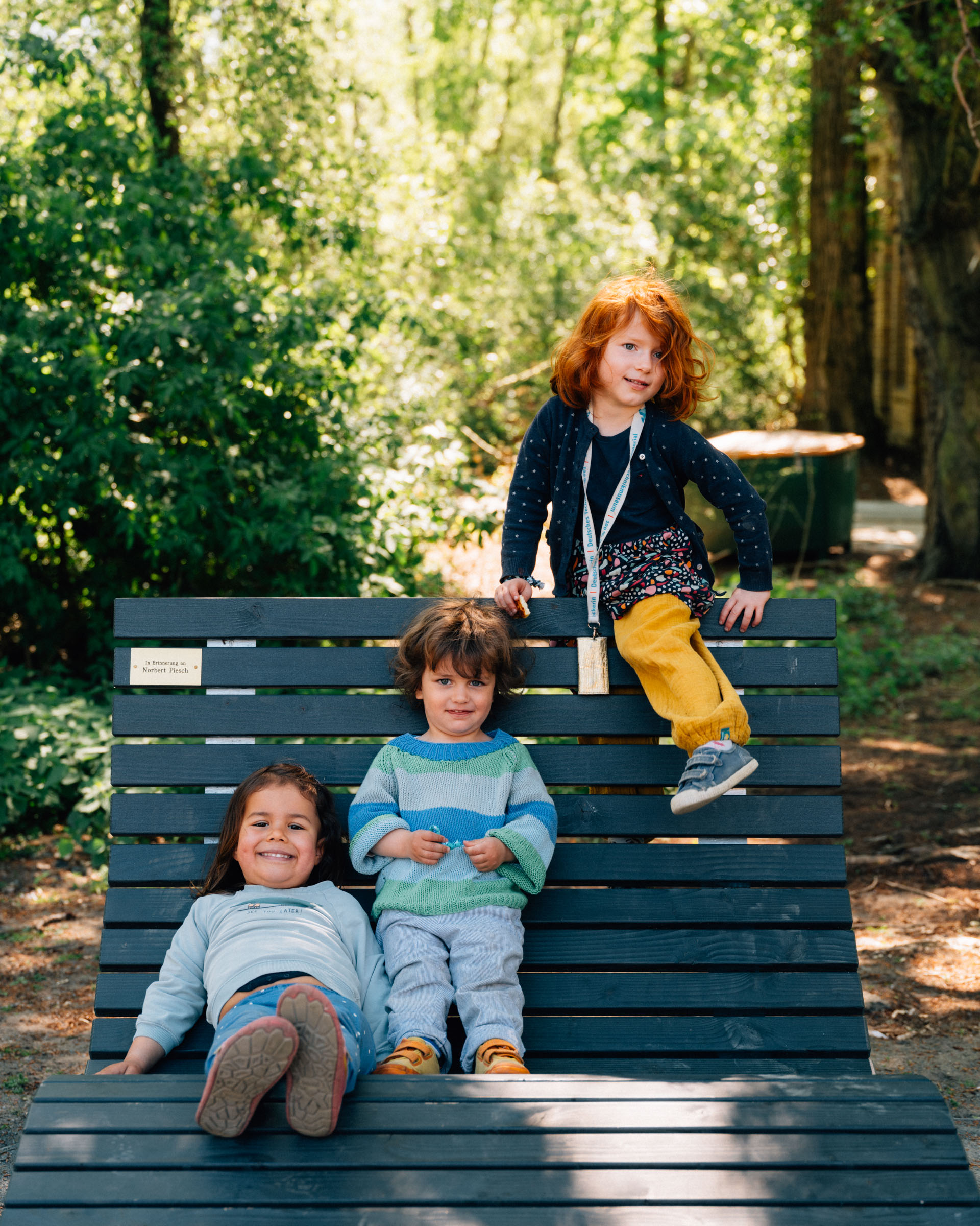 Drei Kinder auf einer gewellten Sitzbank im Park.