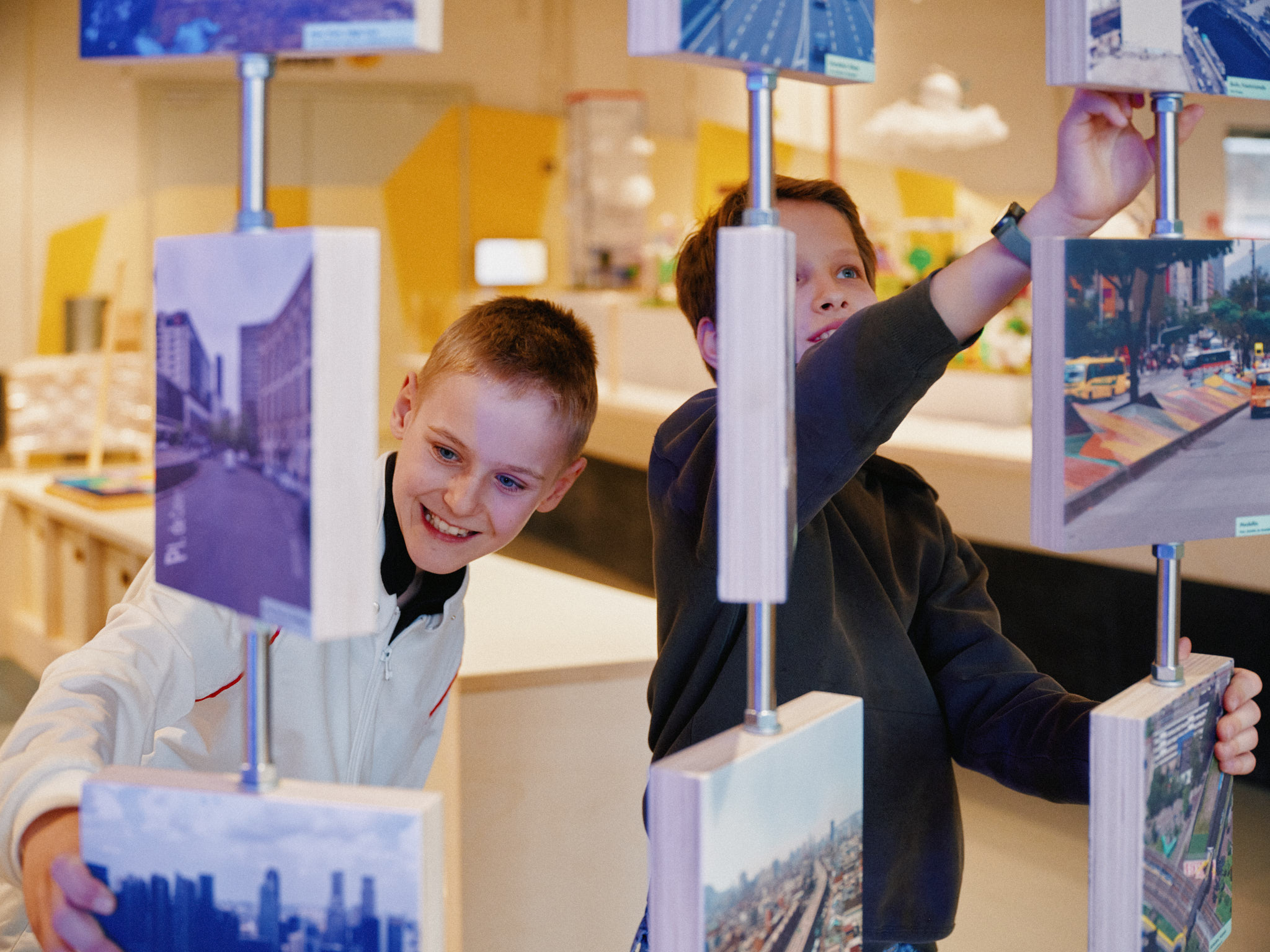 Zwei Jungen stehen an einer Vorrichtung, an der Fotos mit Wendefunktion aufgereiht sind.